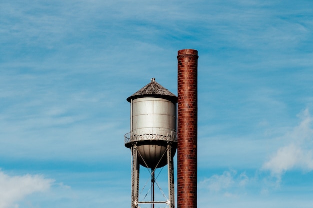 Closeup of a tall water tower with a metal large pipe next to it