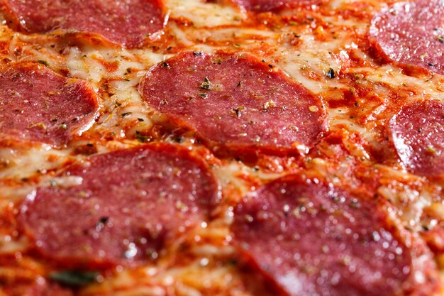 Closeup of tasty appetizing salami pizza with cheese and spices.