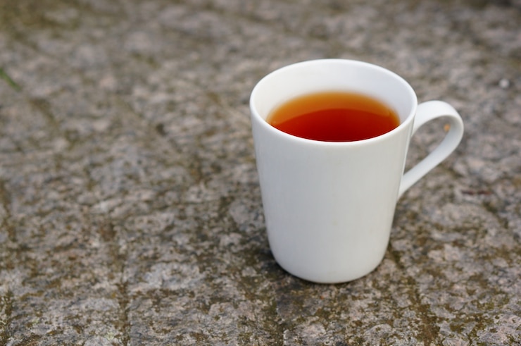 Free Photo closeup of tea in a white cup on the ground under the lights with a blurry background