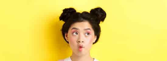 Free photo closeup of teen asian girl pucker lips and looking funny at camera standing with glamour makeup and