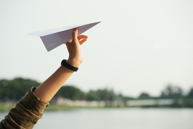 closeup of a teenage hand throwing the paper plane