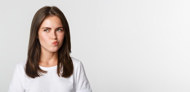 Closeup of thoughtful pretty girl looking upper left corner doubtful thinking over white background