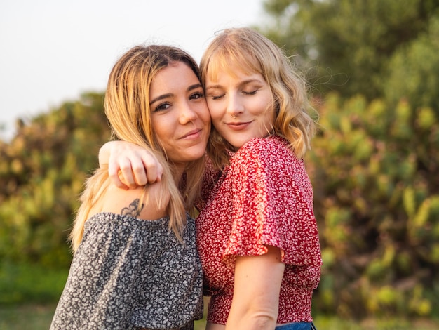 Closeup of two cute hugging female friends posing in the park