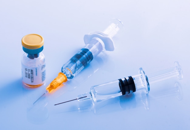 Closeup of two syringes beside a vial of vaccine for flu, COVID-19, measles or other diseases