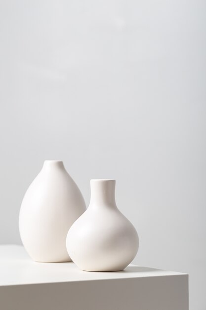 Closeup of two white clay vases on the table under the lights on white