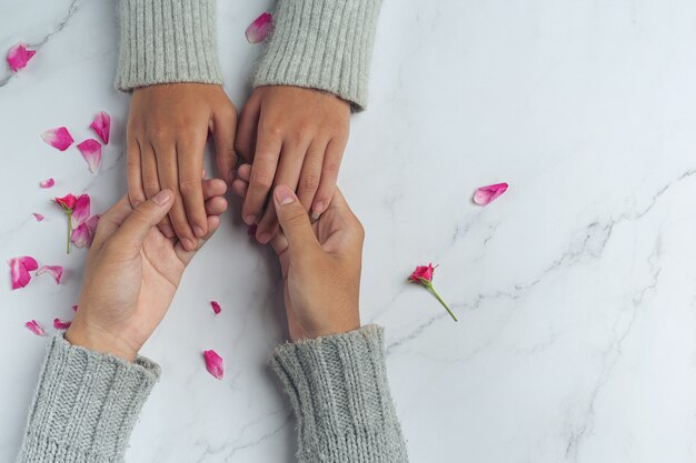 Closeup on two young lovers holding hands at a table.