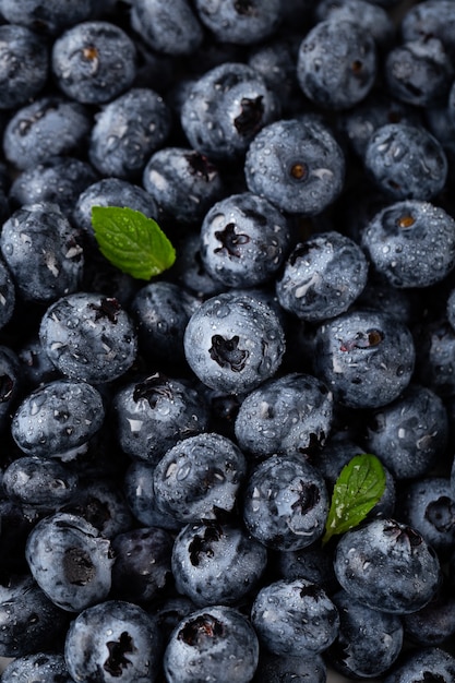 Closeup vertical shot of blueberries with water droplets and leaves