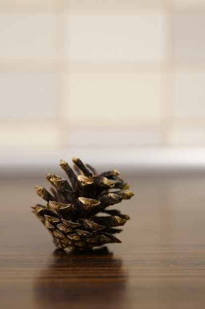 Closeup vertical shot of a pine cone on a wooden table