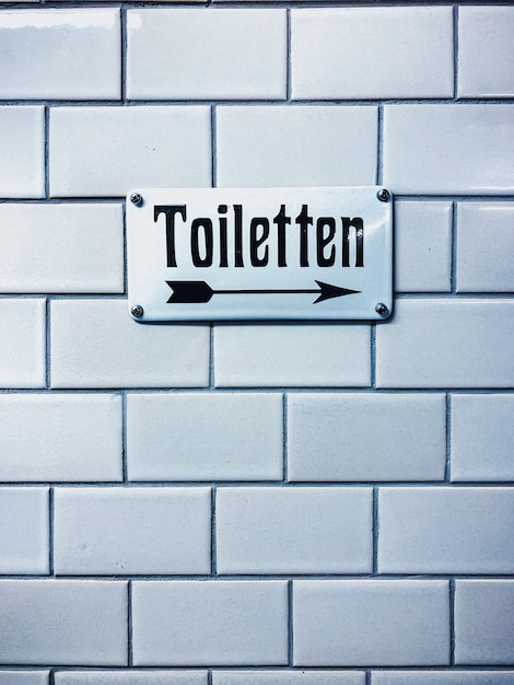 Colpo verticale del primo piano di un segno della toletta con una scrittura tedesca