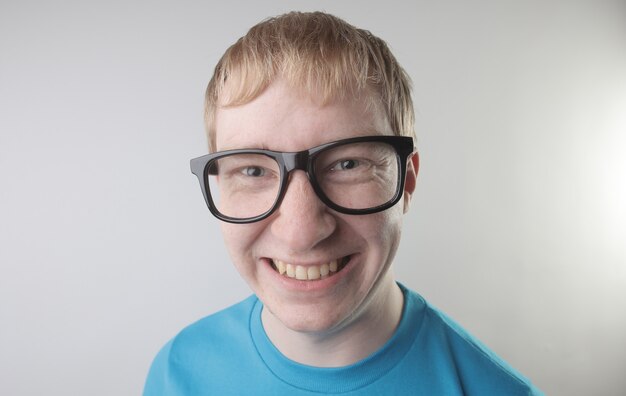 Closeup view of a caucasian male wearing a blue t-shirt and eyeglasses making funny face gestures