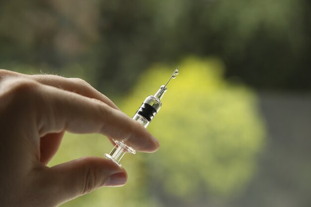 Closeup view of a female holding a syringe, on a blurred background