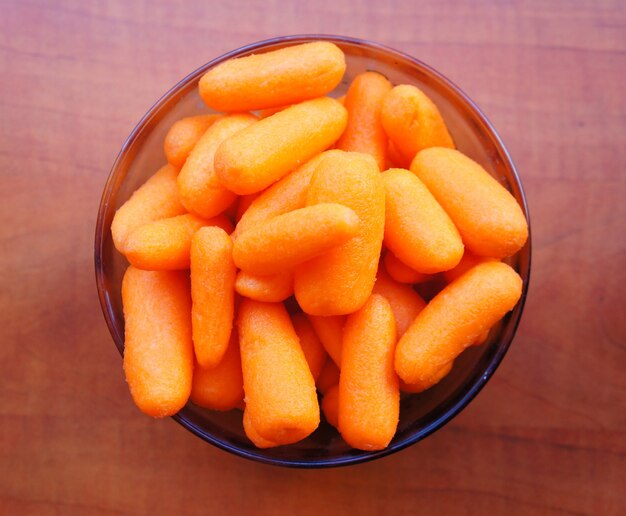 Closeup view of fresh carrots in a bowl on a wooden surface