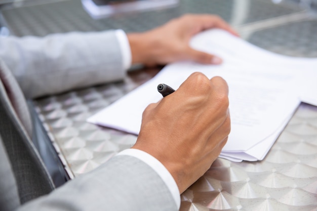 Closeup view of male hand signing paper