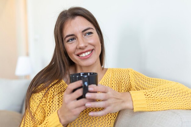 Closeup view of young woman with cup of hot drink at home blank space People drinks and leisure concept happy young woman with cup of tea or coffee at home