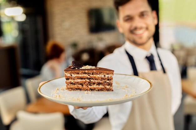 Closeup of waiter holding plate with slice of cake