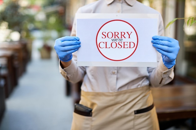 Closeup of waitress holding closed sign due to COVID19 epidemic