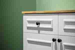 Free photo closeup of a white cabinet with black handles on a green wall background