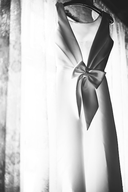 Free photo closeup of white wedding dress hanging by the window grayscale