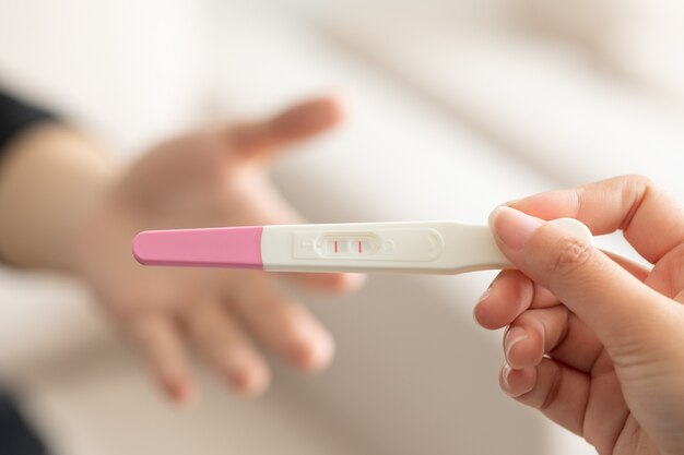 남편에게 긍정적인 임신 테스트를 제공하는 아내의 근접 촬영