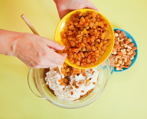 Closeup of woman adds raisin into dough