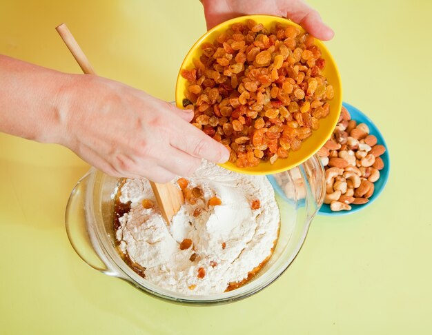 Closeup of woman adds raisin into dough