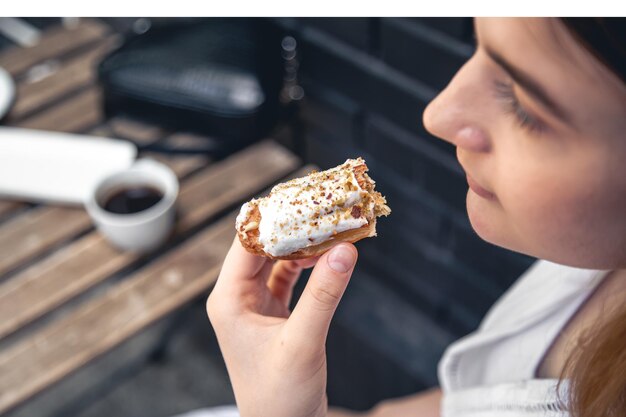 Closeup a woman eats an appetizing eclair