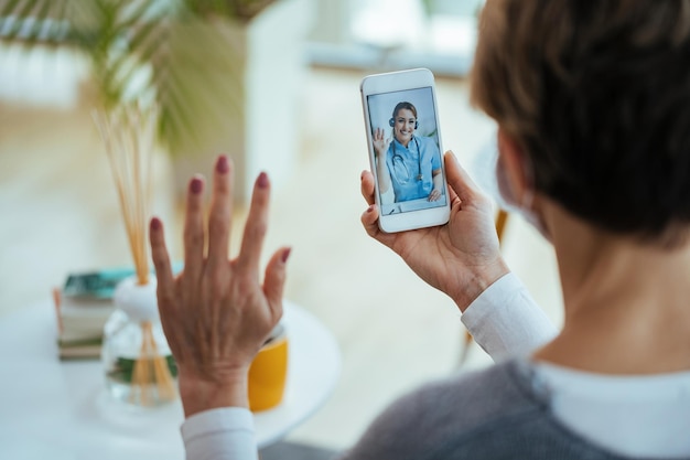 Closeup of woman greeting her doctor while using smart phone and having video call Focus is on female doctor on touchscreen