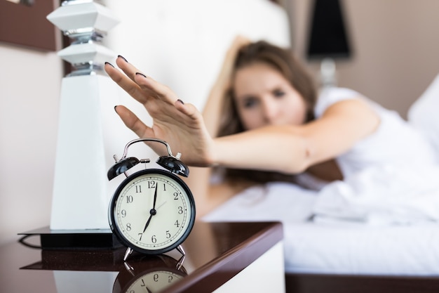 Closeup on woman hand reaching to turn off alarm clock in the morning