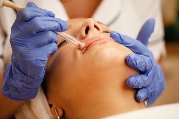 Closeup of woman having vacuum procedure on her lips during treatment at beauty salon