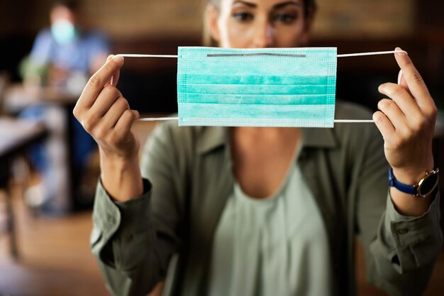 Closeup of woman holding protective face mask in a cafe