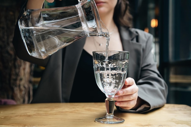 クローズアップ女性がカフェのグラスに水を注ぐ