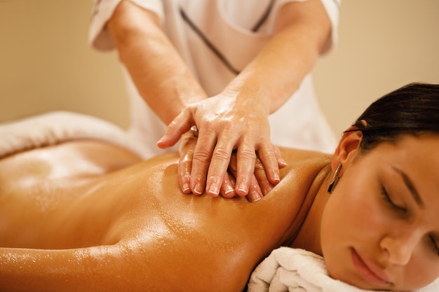 Foto gratuita primo piano della donna che si rilassa durante il massaggio alla schiena al salone della stazione termale
