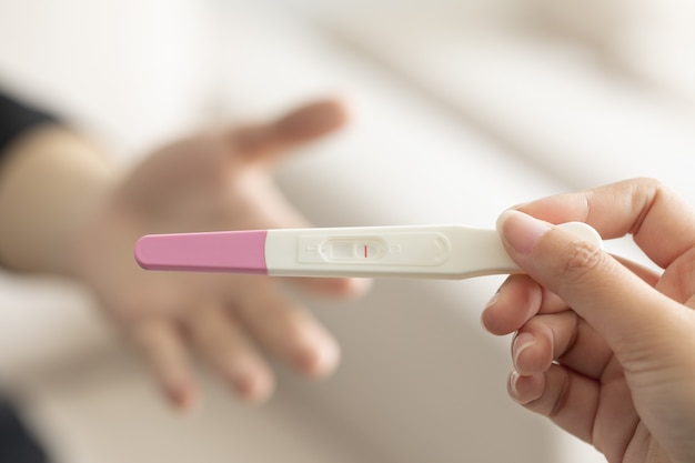 否定的な結果で妊娠検査キットを持っている女性の手のクローズアップ