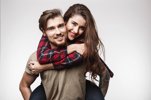 Closeup of woman sitting on man's back, looking happy.