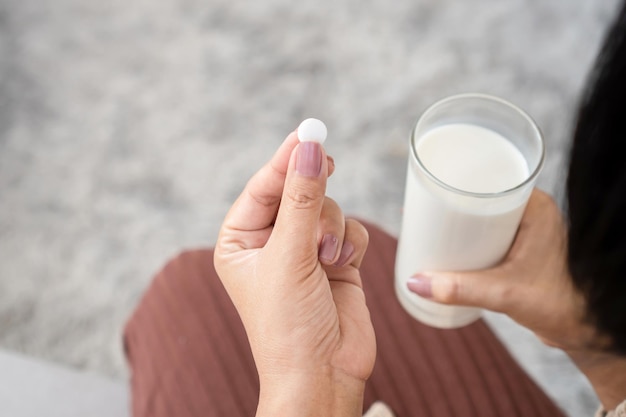 Closeup woman taking medicine with a glass of milk