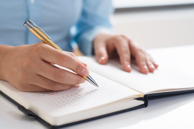 Closeup of woman using diary and scheduling