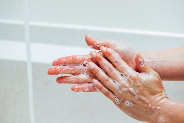 화장실에서 손을 씻는 동안 비누를 사용하는 여성 클로즈업