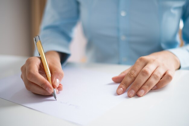 Closeup of woman writing on sheet of paper