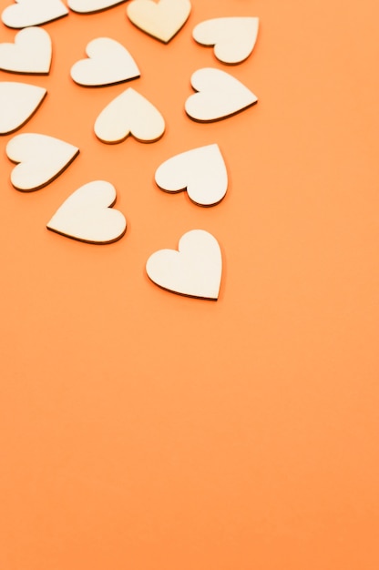 Closeup of the wooden shaped hearts on the orange surface - space for text