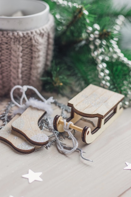 Closeup of a wooden sledge ornament surrounded by Christmas decorations on the table