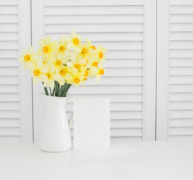 白いシャッターの上の花瓶に黄色い水仙の花のクローズアップ。きれいなプロヴァンス風の装飾