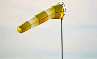 Foto gratuita primo piano di una manica a vento gialla e bianca che galleggia nell'aria durante la luce del giorno