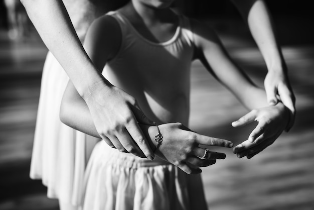 Closeup of young ballerina practice ballet with teacher grayscale