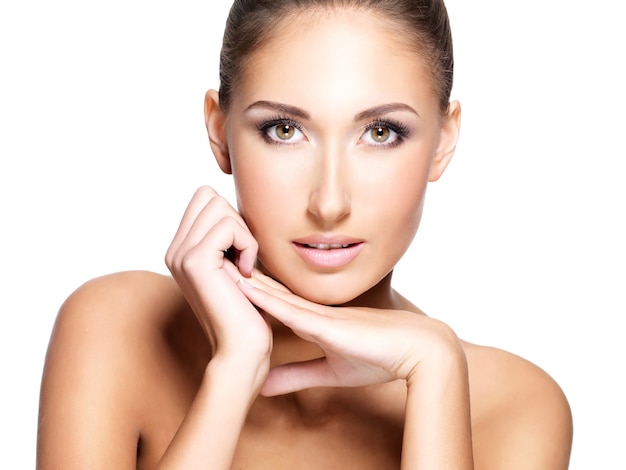 Closeup of a young beautiful woman with clean fresh skin touching her face