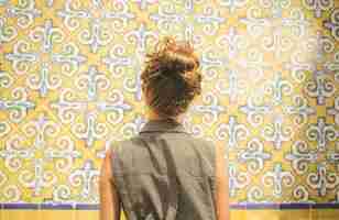 Free photo closeup of a young caucasian female in gray collared sleeveless top facing the floral wall