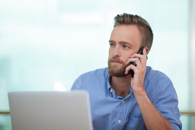 Closeup of Young Man Calling on Phone with Laptop