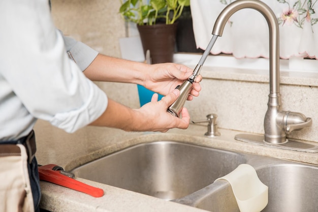closeup of a young man inspecting and repairing a kitchen faucet