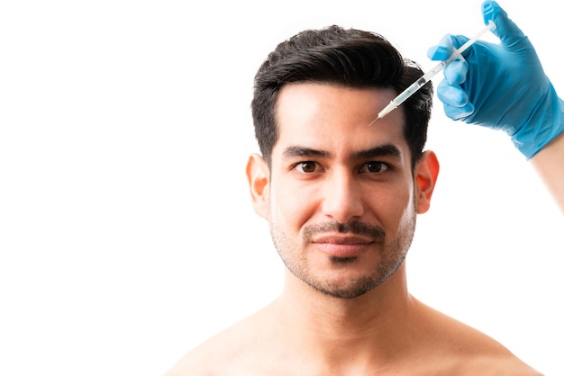 Closeup of young man receiving botox injection on his face on white background