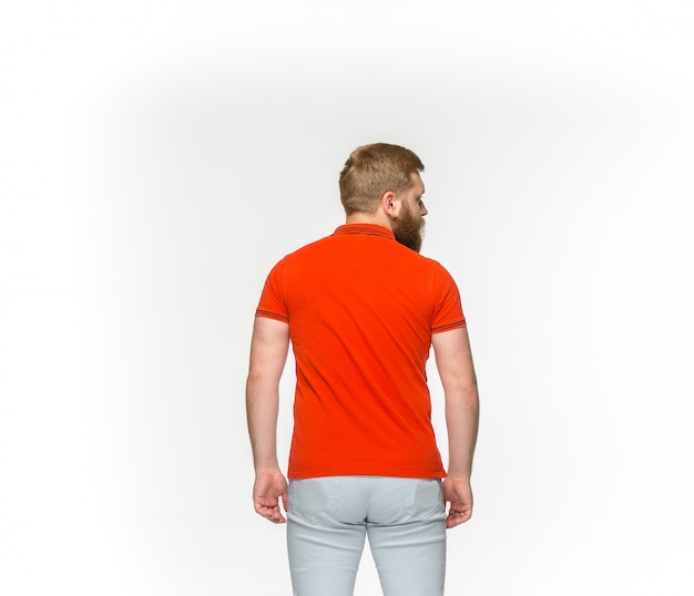 白い背景に分離された空の赤いtシャツで若い男の体のクローズアップ。設計コンセプトのモックアップ