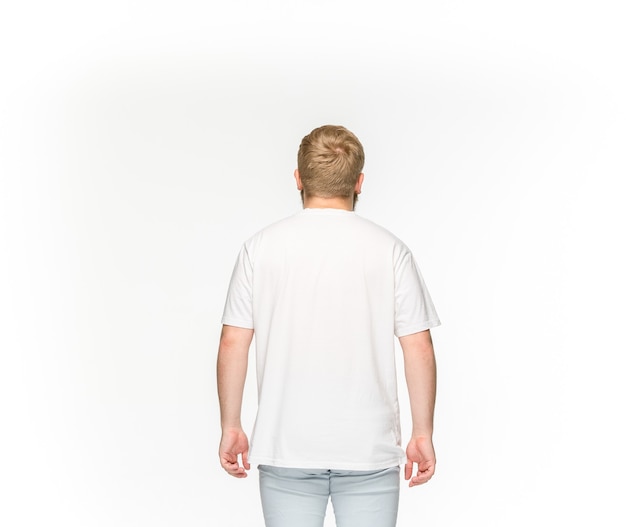 白で隔離される空の白いtシャツで若い男の体のクローズアップ。